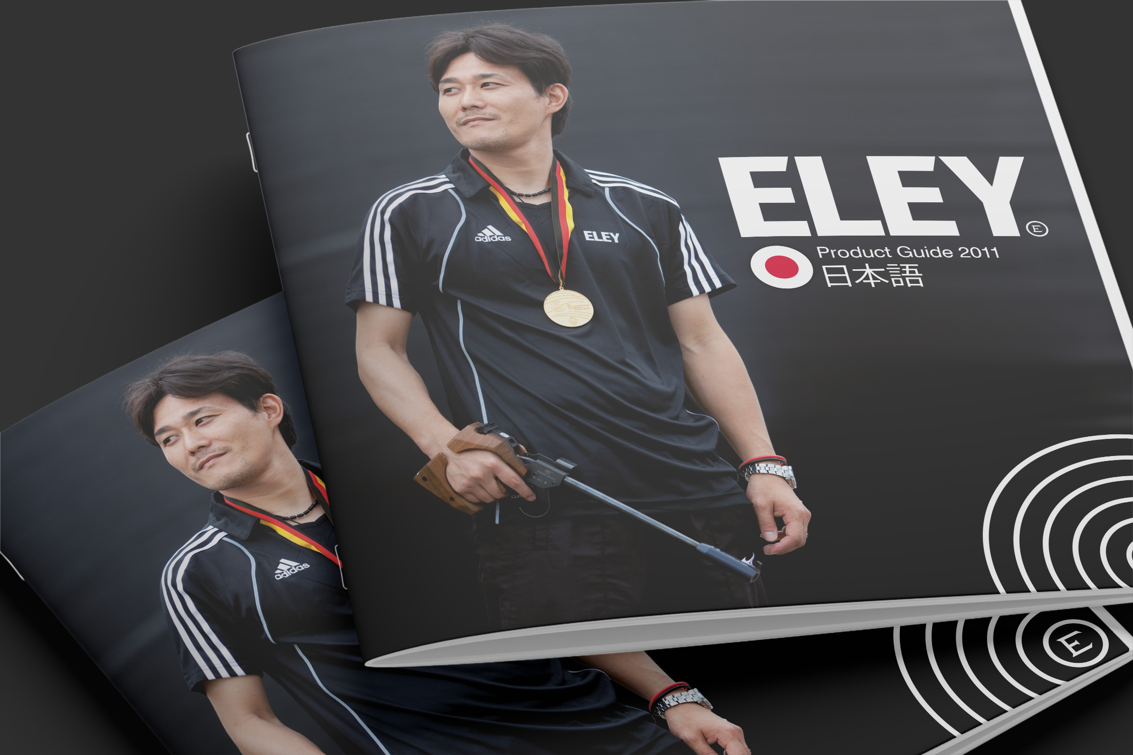 Close-cropped image showing the Japanese-language Eley 2011 product guides. On the cover a Japanese competetive shooter wearing a gold medal holds a pistol and looks to his right against a dark background.