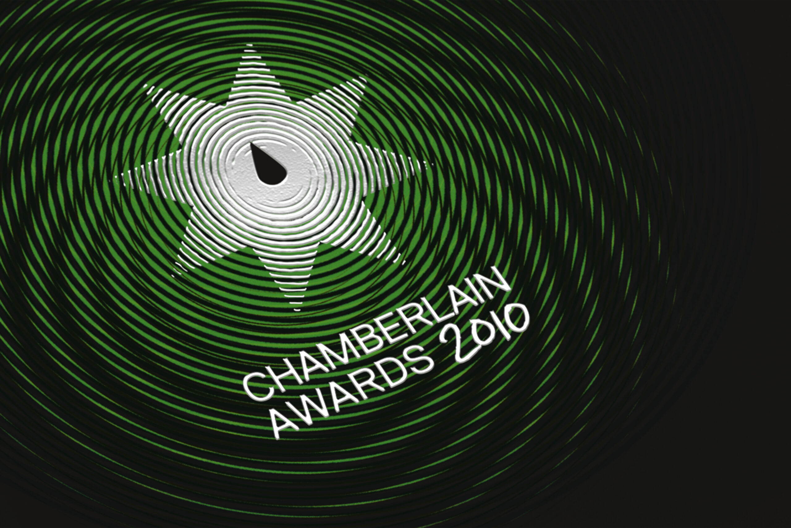Close up image from cover of Chamberlain Awards 2010 brochure. The image shows the awards logo embossed in silver foil. The centre of the logo shows a drop of water against a background of green and black ripples.