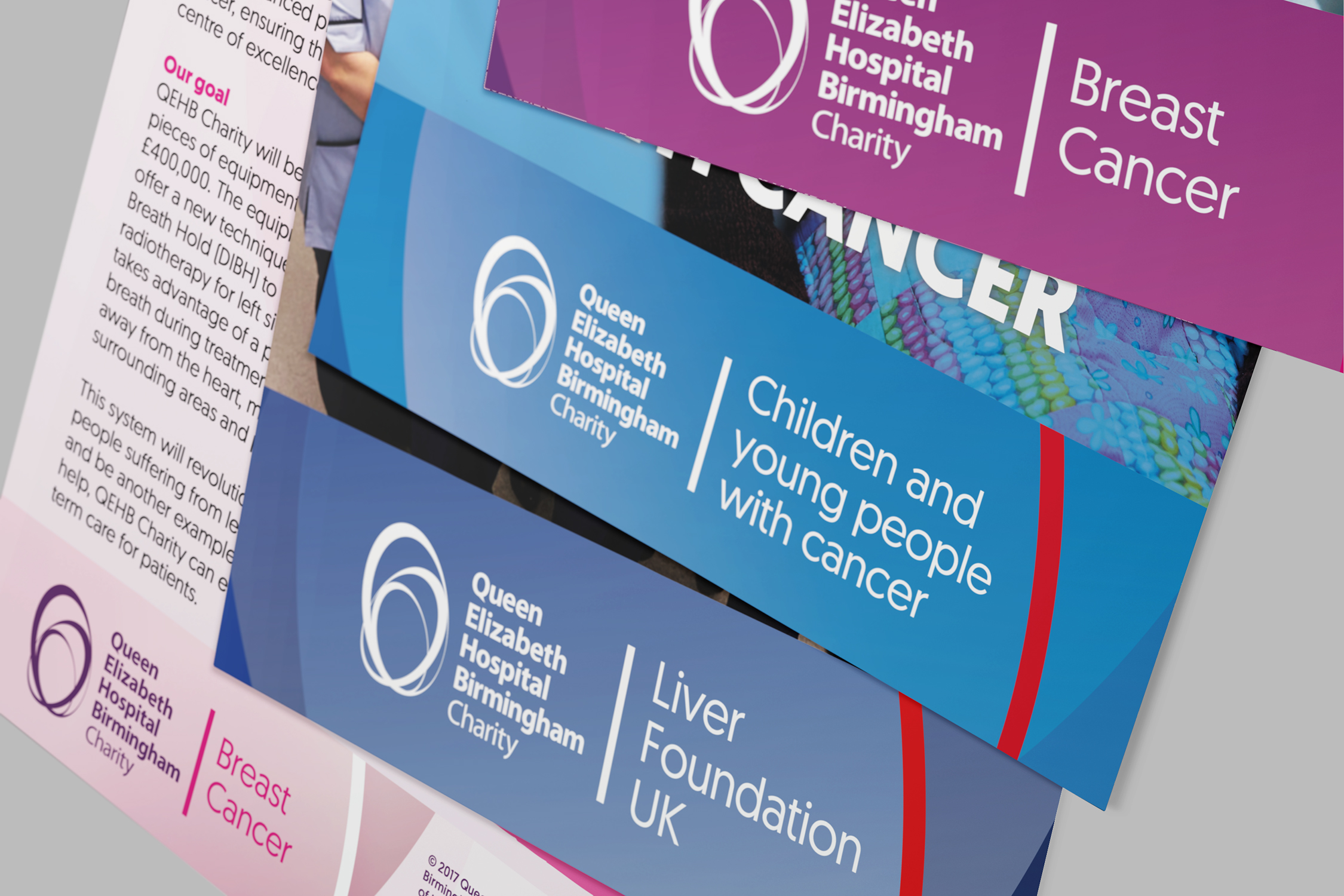 A variety of colourful leaflets are scattered on a desktop. Each leaflet incorporates a different QEHB Charity fund logo.